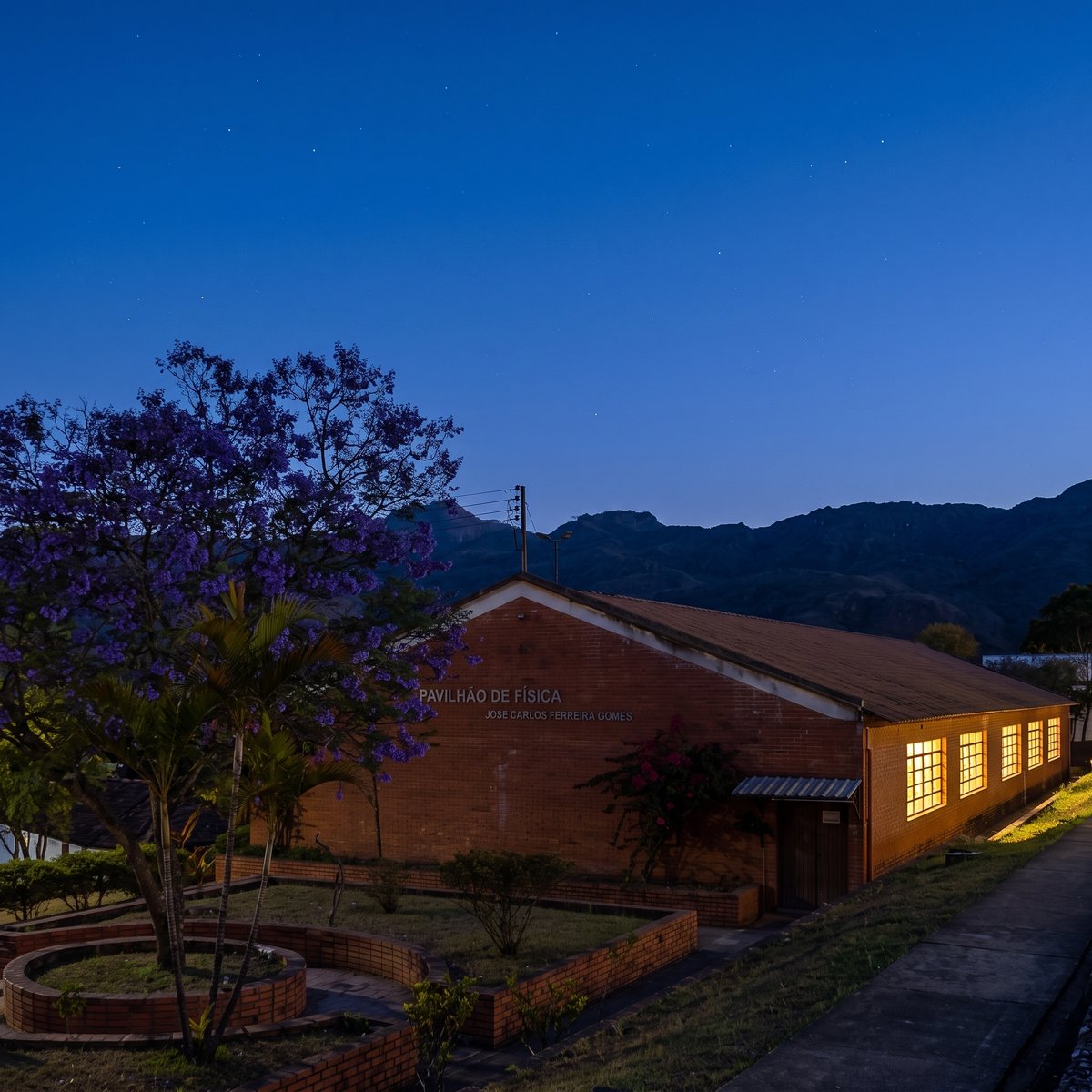 O Pavilhão de Física do IFMG campus Ouro Preto ao anoitecer, com as janelas do laboratório acesas e a serra ao fundo